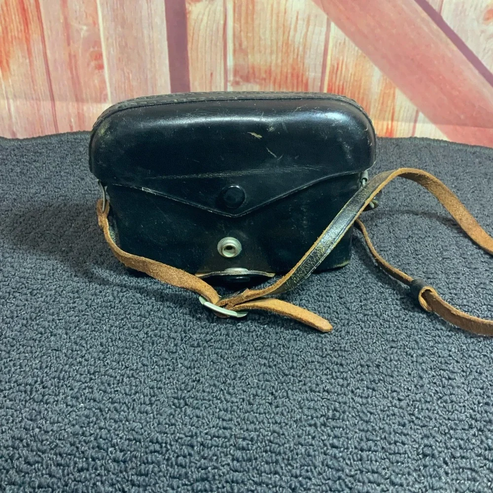 Vintage Petri camera with leather strap and cover.